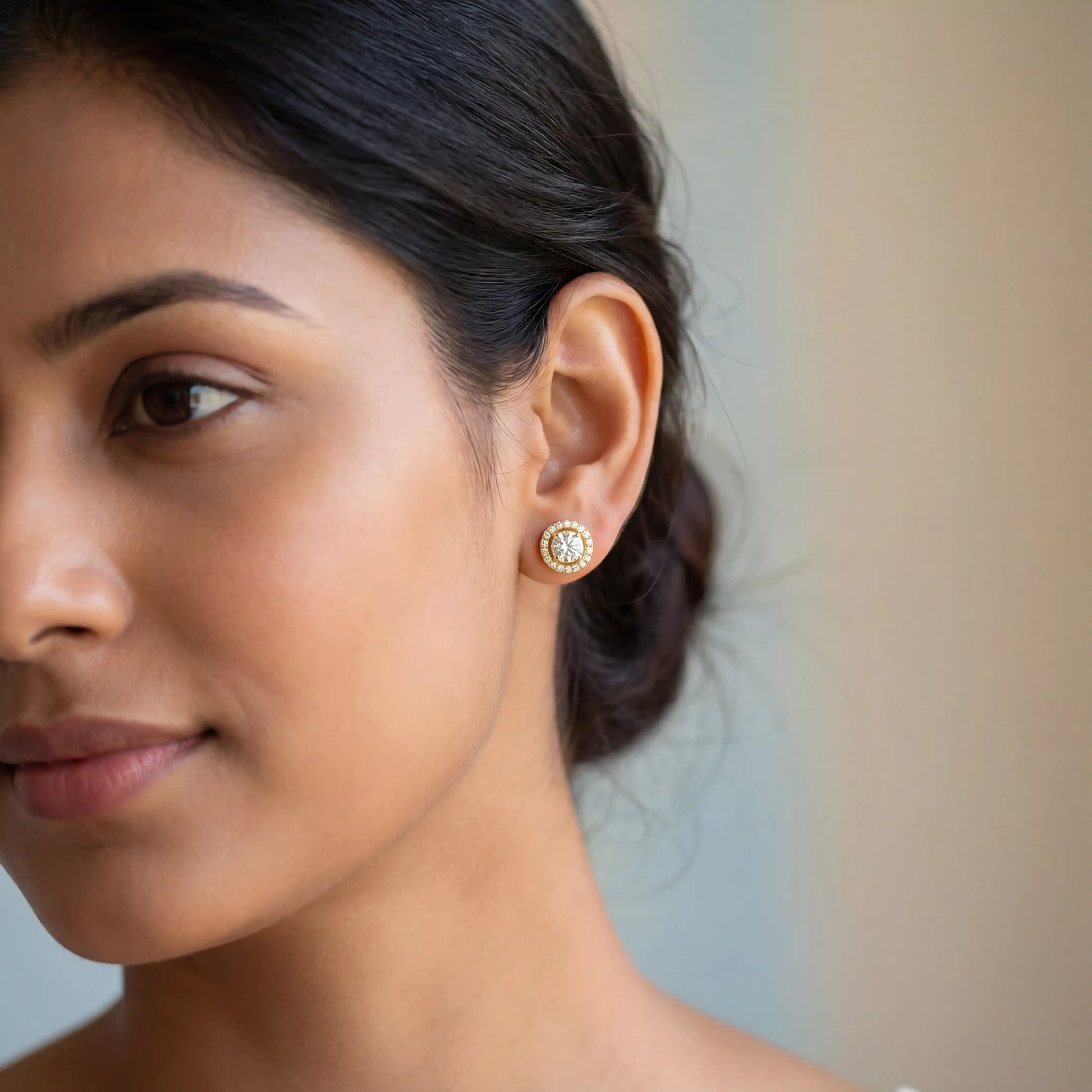 Close-up of a woman wearing a gold earring with a blurred background